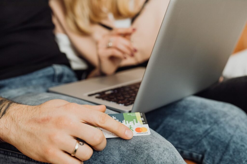A couple using a laptop for online shopping, holding a credit card in a cozy setting