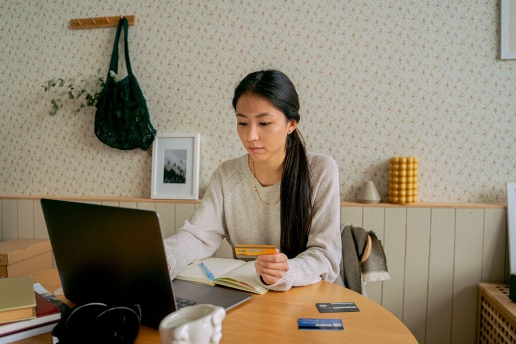 A woman using a laptop and credit card for online shopping at a cozy indoor setting