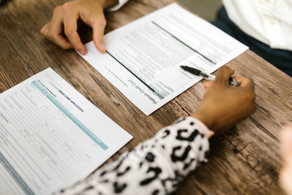 Close-up of two people reviewing and filling out a credit card application on a wooden table