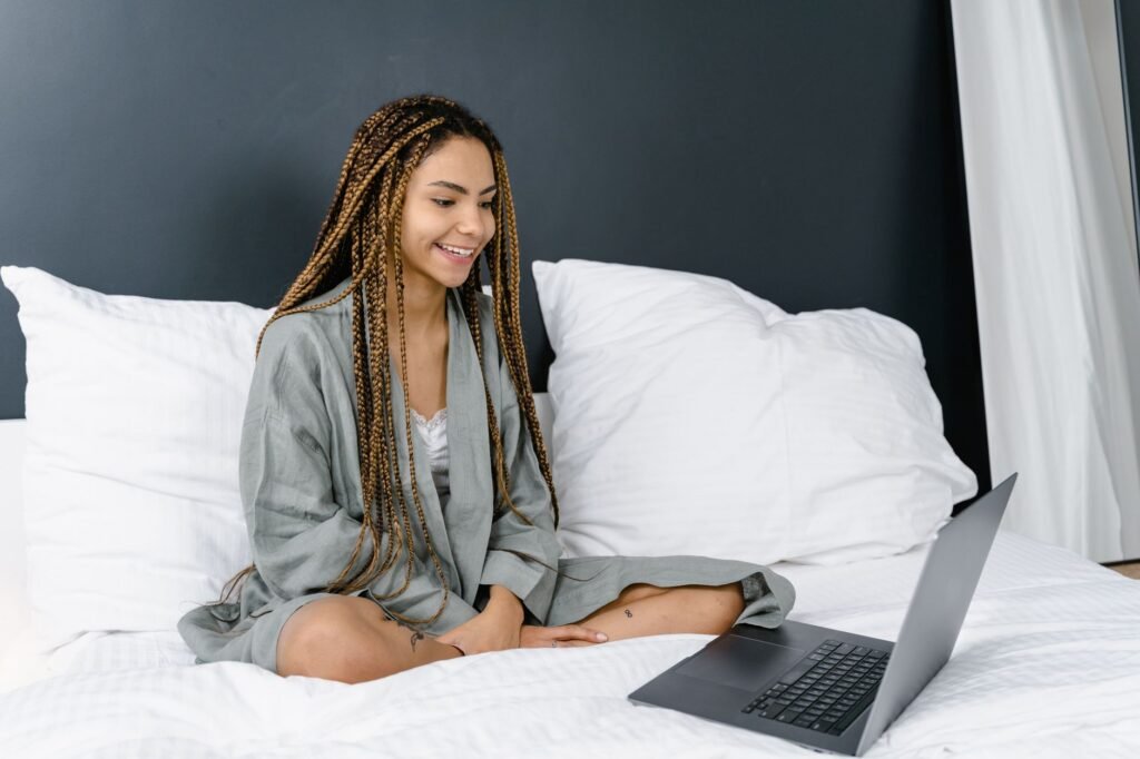 Smiling young woman writing a message on her laptop at home