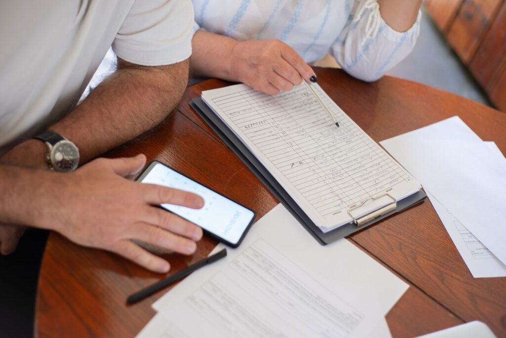 Senior couple examining bills and documents with smartphone and clipboard at home