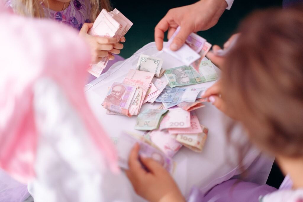 A child and adult hands sorting colorful banknotes on a table, symbolizing financial education