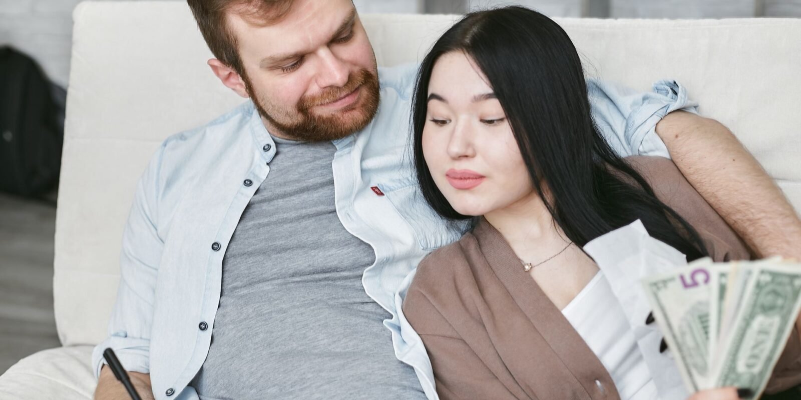 A couple sits indoors planning their finances and looking at money