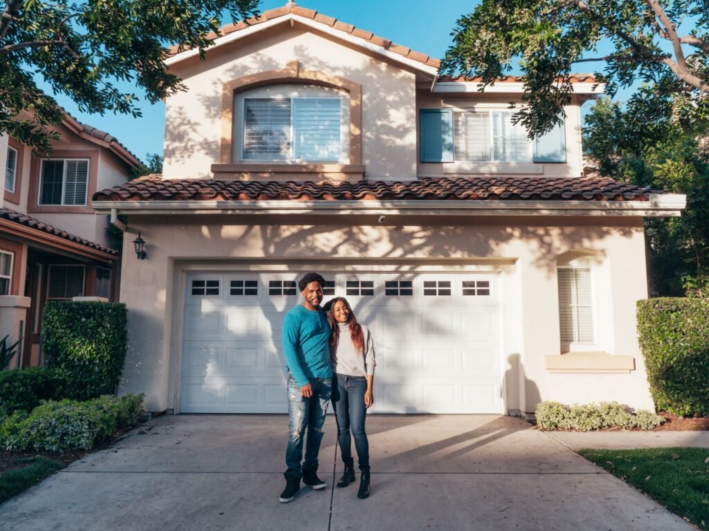 A joyous couple stands together in front of their newly purchased house, symbolizing new beginnings