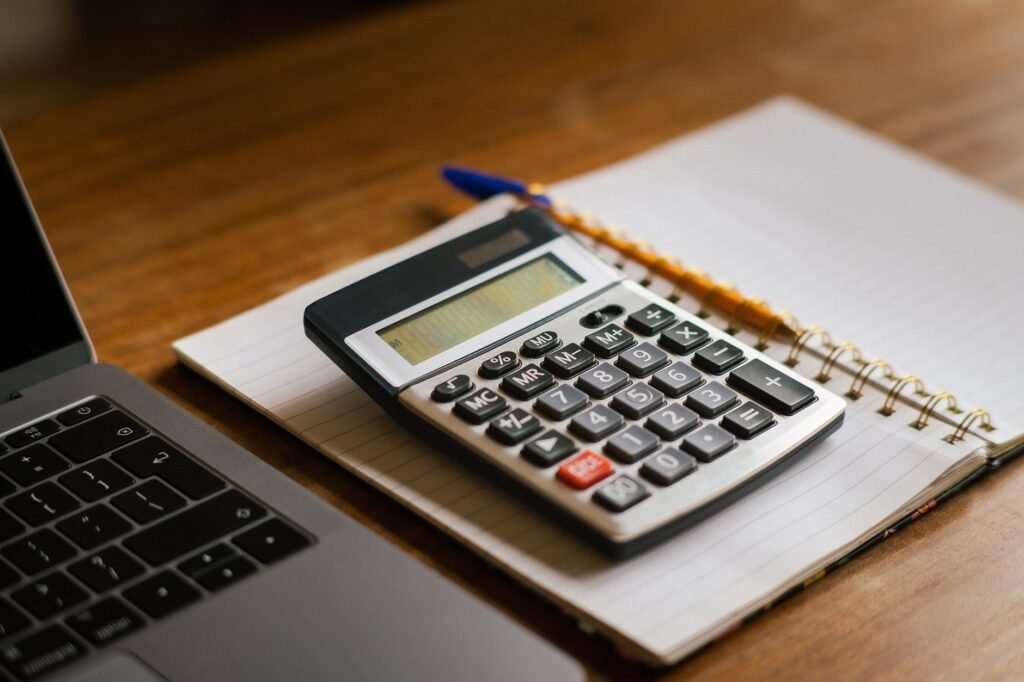 Calculator and open laptop on wooden desk