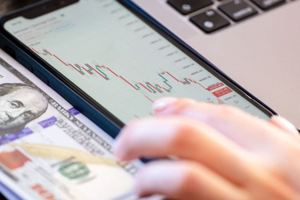 Close-up of a smartphone displaying stock market data over a dollar bill on a desk