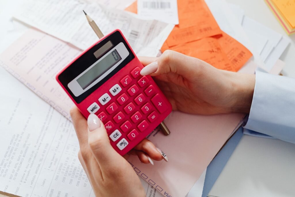Close-up of hands holding a red calculator, managing finances with documents and receipts