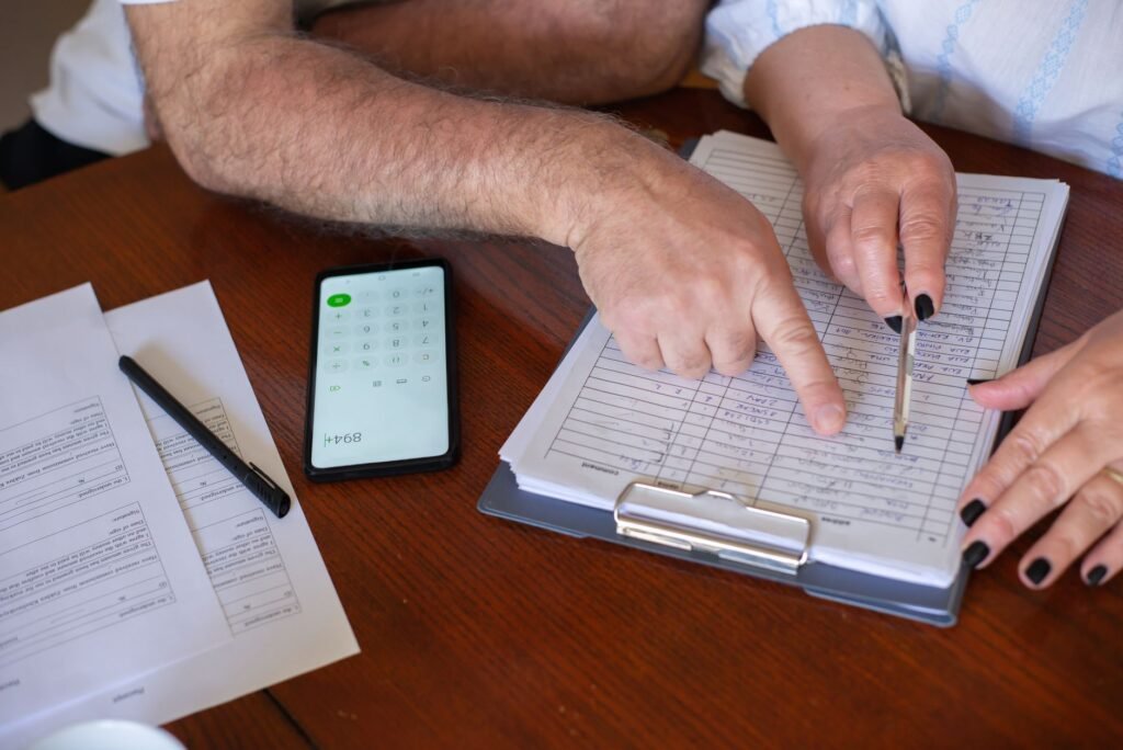 Close-up of hands working on finance planning with documents and a smartphone calculator