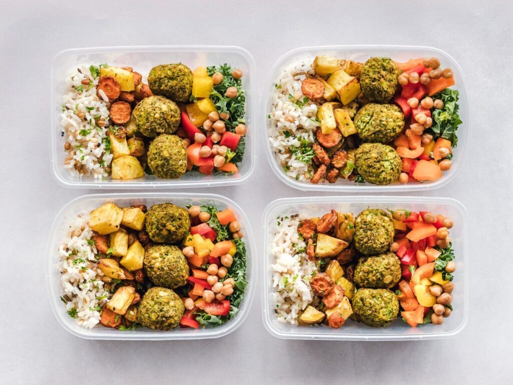 Colorful meal prep containers with falafel, chickpeas, rice, and vegetables for a healthy lifestyle