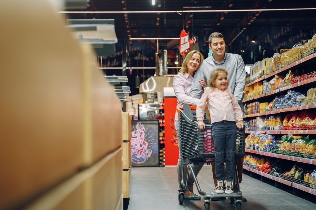 Family enjoying a shopping trip in a supermarket, with a child in a cart and parents smiling