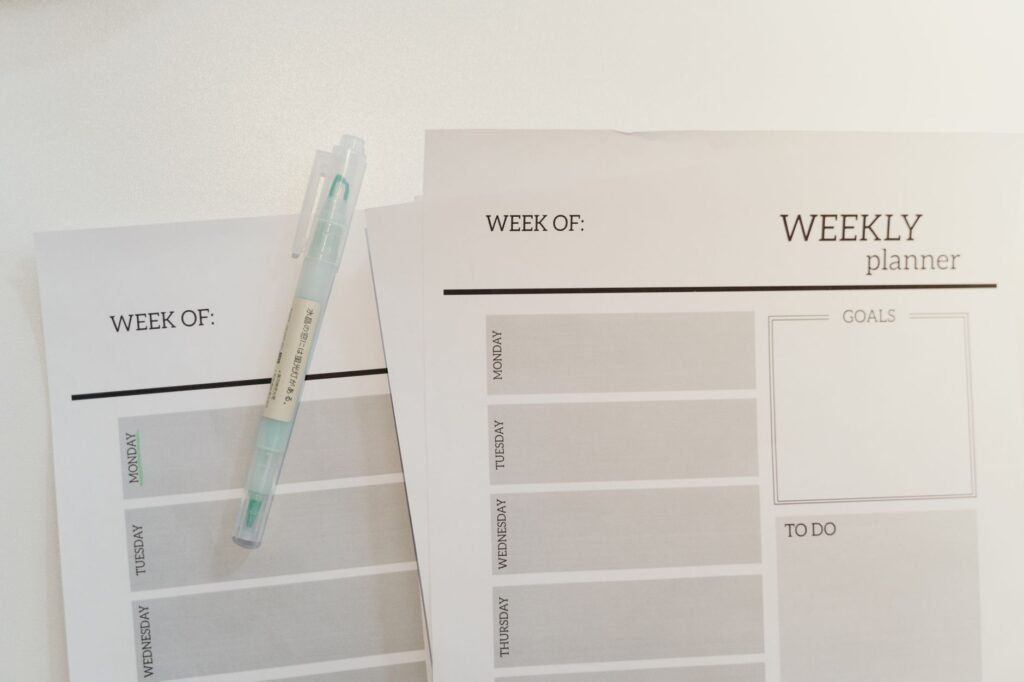 Organized weekly planner sheets with a pen for efficient scheduling and goal setting