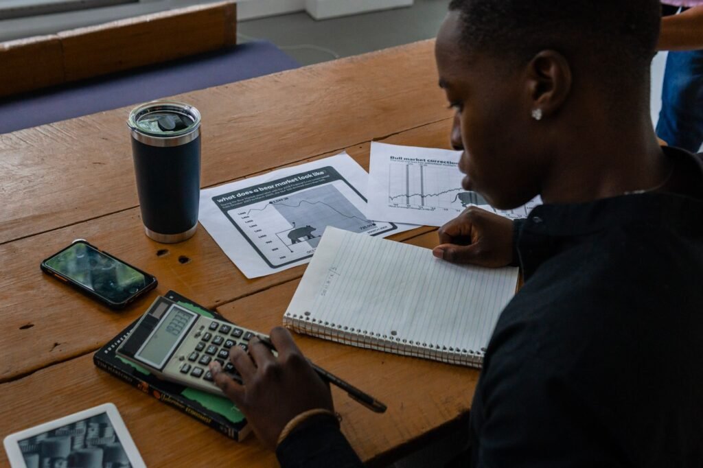 Young professional evaluating financial data using a calculator and notes
